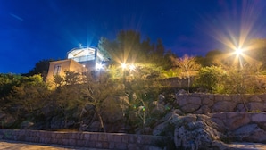 Un edificio con estructura de cúpula, rodeado de muros de piedra y vegetación.