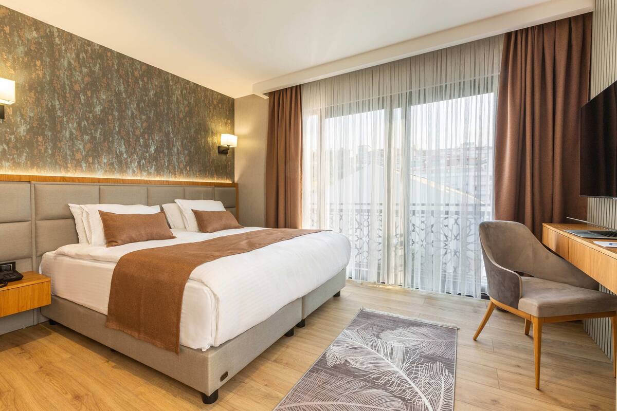 A modern hotel room with a large bed, a desk, and a TV.