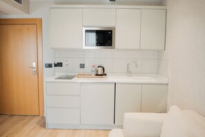 A compact kitchenette with a microwave, a sink, and a coffee maker. - North Star Hotel  (Trabzon)
