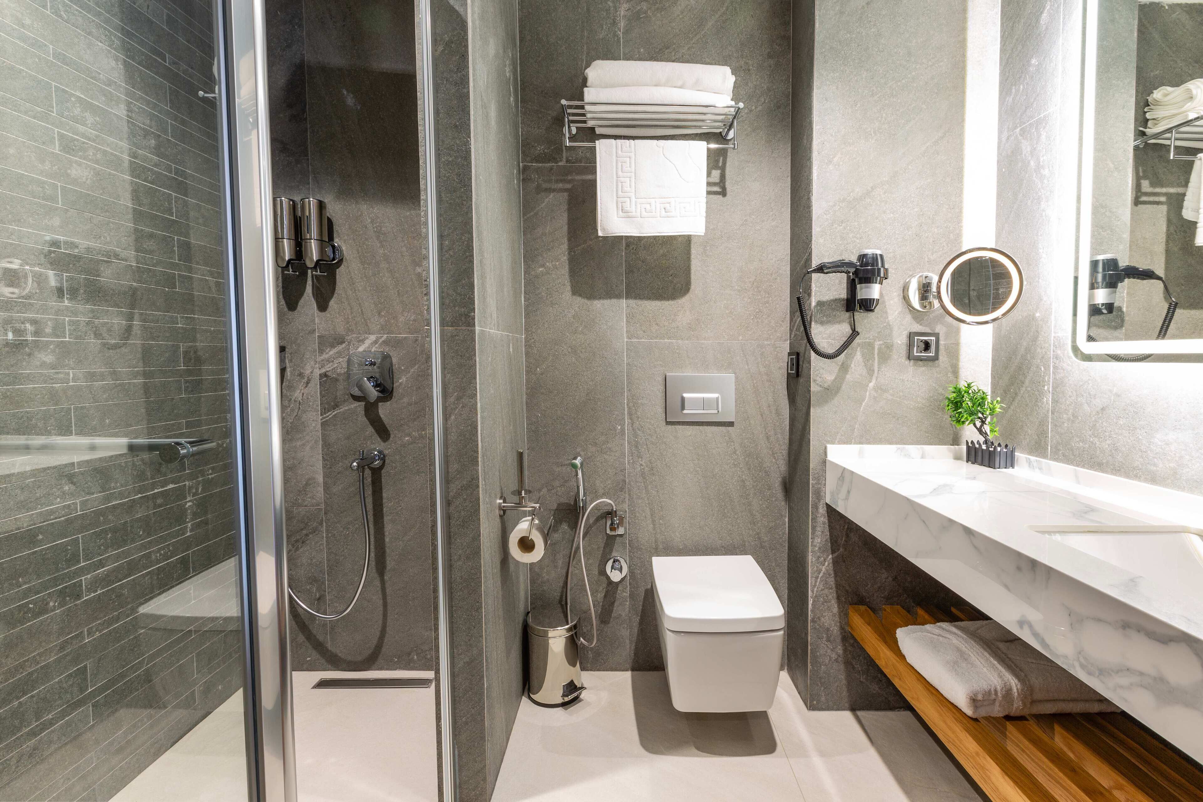 Un baño moderno con cabina de ducha de vidrio, inodoro blanco y tocador de mármol.