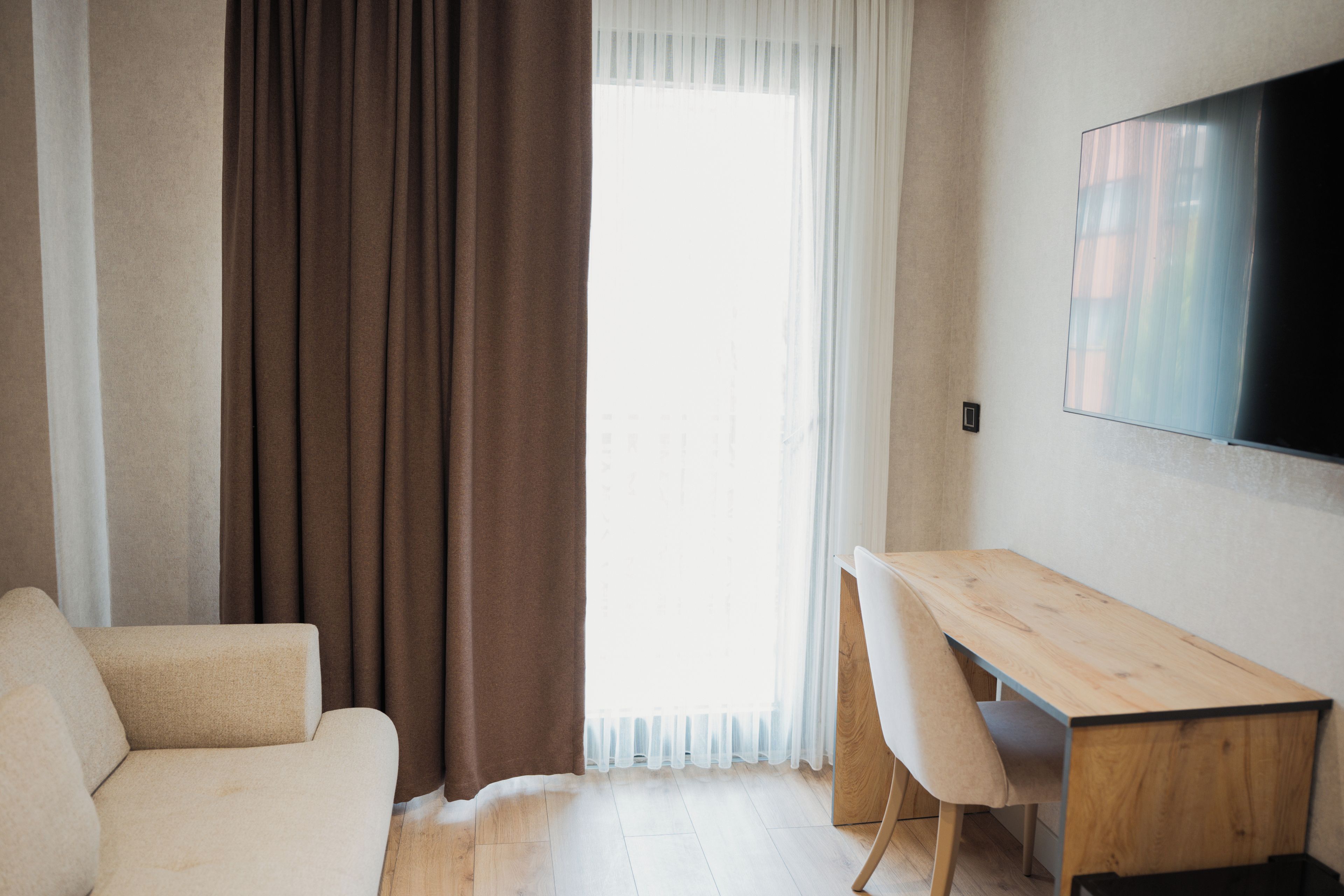 Ein modernes Zimmer mit einer Couch, einem Holztisch und einem an der Wand befestigten Fernseher.