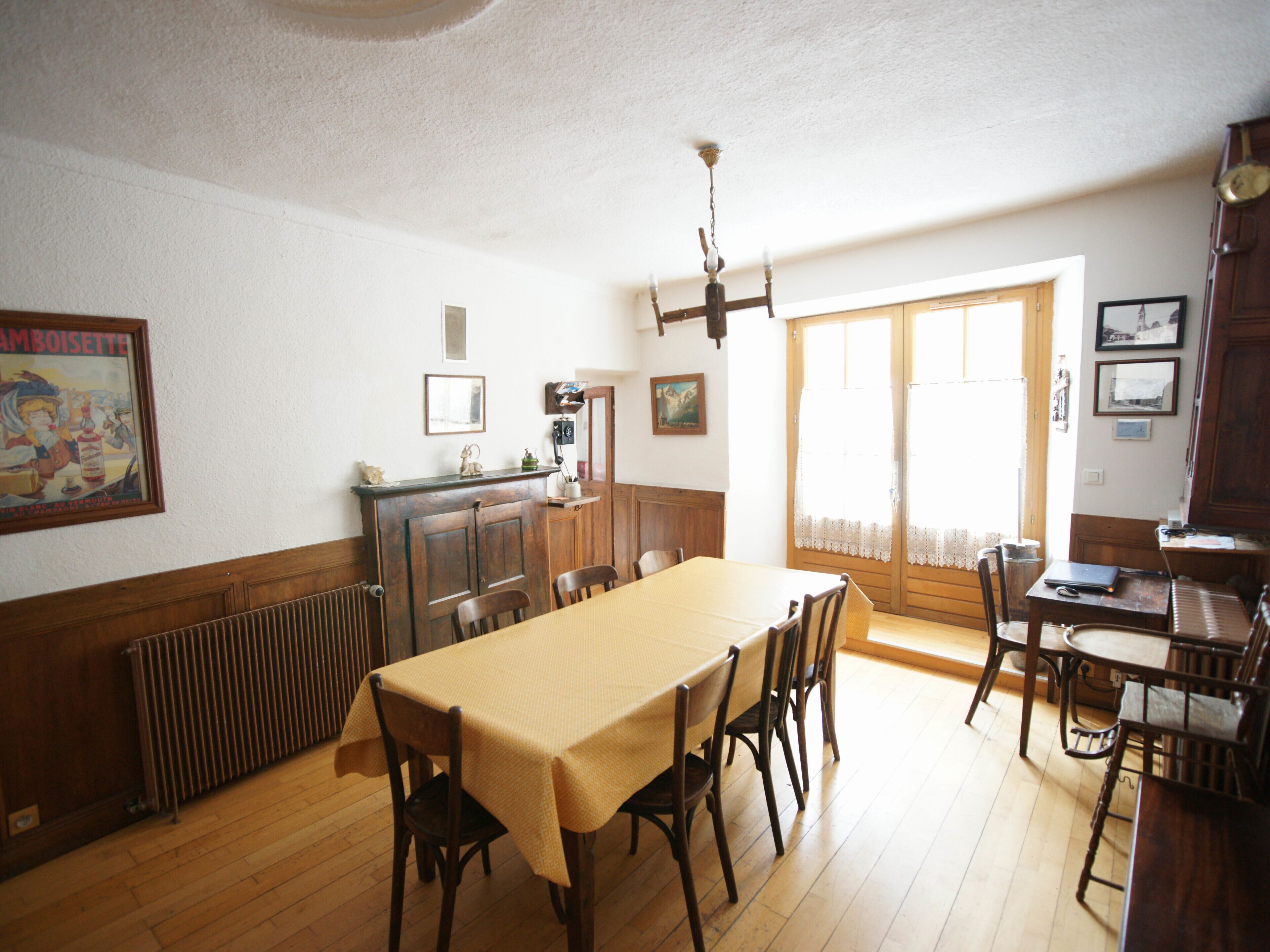 A dining room with a wooden table and chairs, a radiator, and a chandelier.