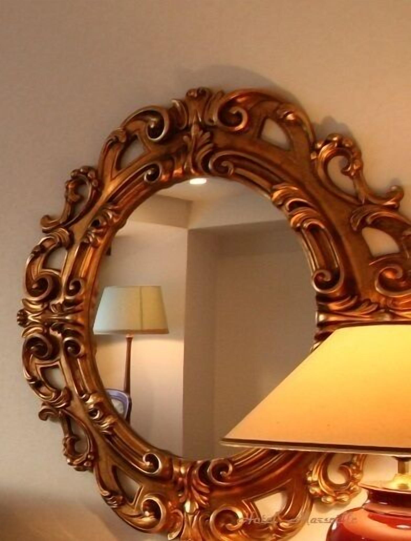 A mirror with an ornate frame, a lamp, and a lamp stand.
