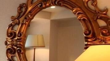 A mirror with an ornate frame, a lamp, and a lamp stand.