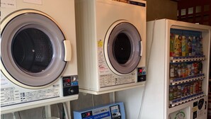 A laundromat with multiple washing machines, a coin-operated dryer, and a vending machine with beverages. - Annex Hotel Mimatsu (Mito)