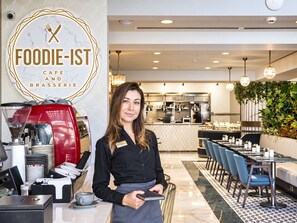 A cafe and brasserie interior with a coffee machine, seating area, and a sign reading 'FOODIE-IST'. - Sura Luxury Million & Spa (Istanbul)