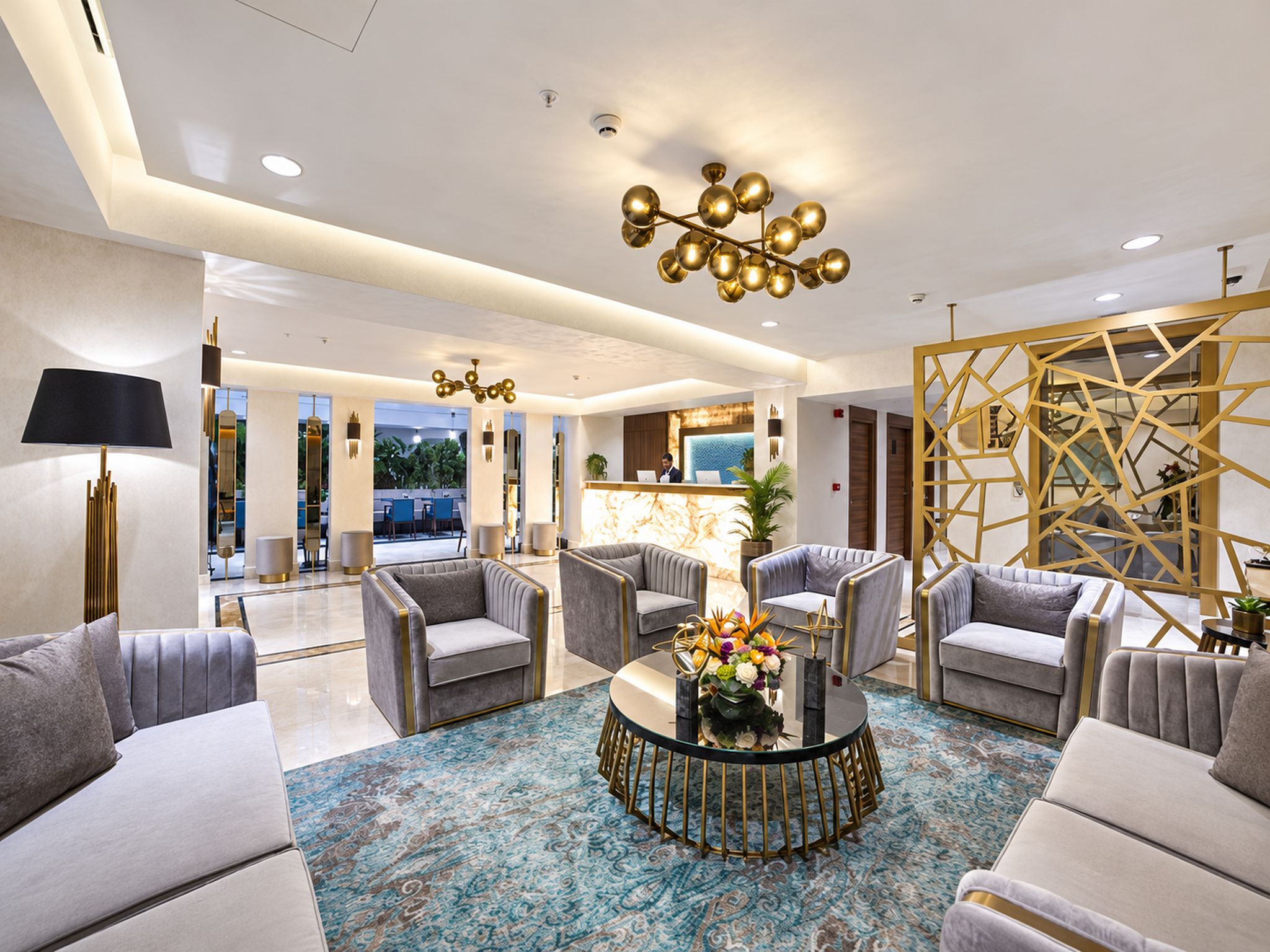Un moderno vestíbulo de hotel con mostrador de recepción, zona de estar e iluminación decorativa.