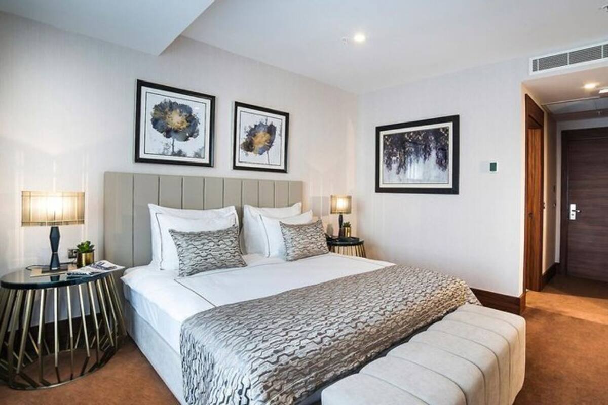 A modern bedroom with a large bed, two bedside tables, and framed artwork on the walls.