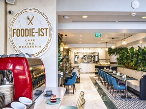 L’intérieur d’un restaurant avec un comptoir en marbre, un espace salon et une cuisine ouverte visible au fond.
