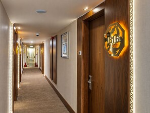 A hotel hallway with wooden doors, a framed picture, and a sign with the number 1316. - Sura Luxury Million & Spa (Istanbul)