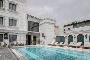 Un hotel con piscina, sillas de descanso y acceso a un spa.