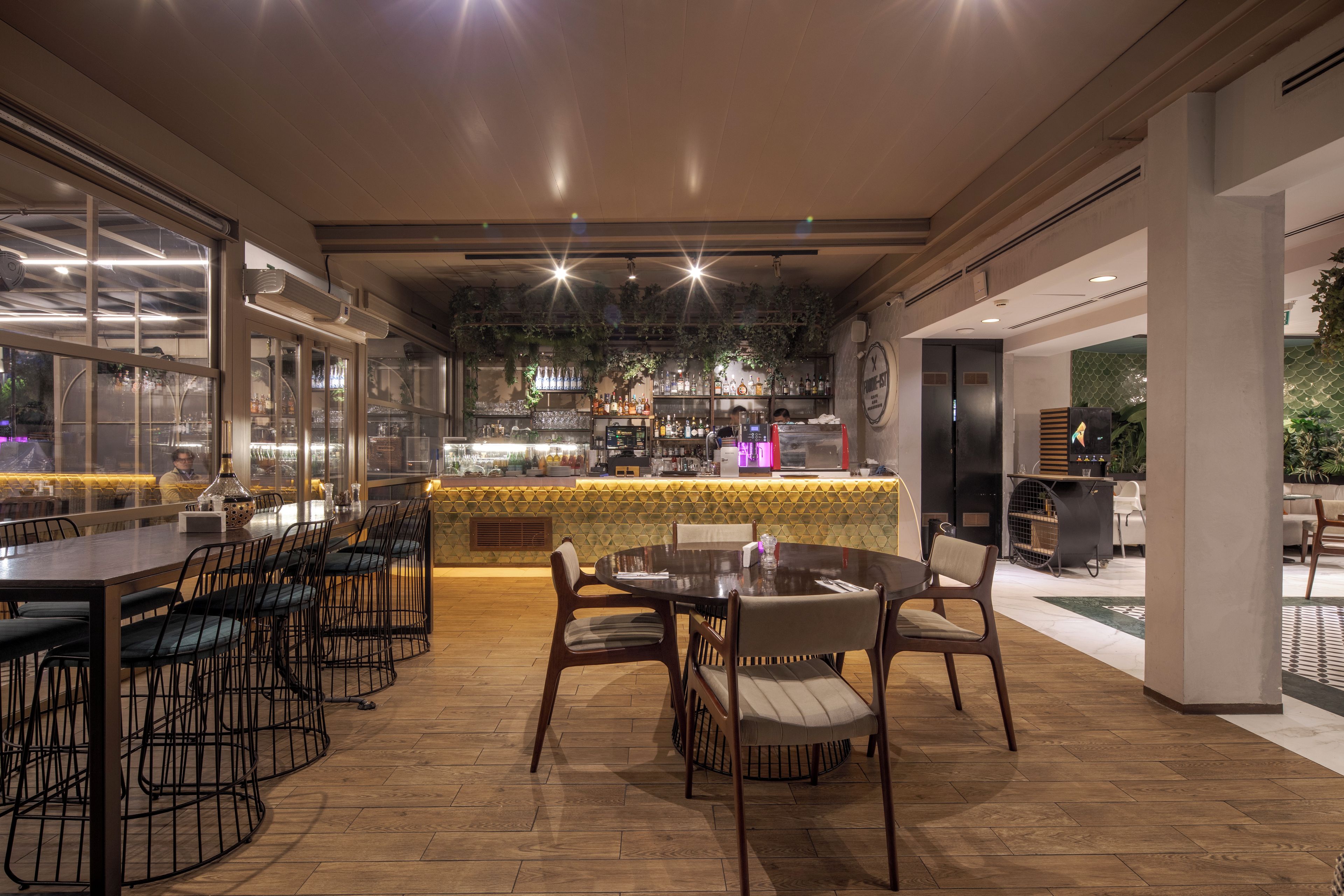 A restaurant with a bar area, wooden flooring, and a view of the street.