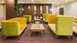 Un vestíbulo con sillones amarillos, una mesa de centro de madera y una alfombra a rayas.