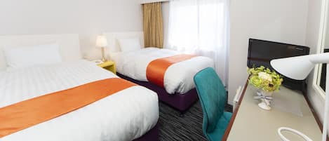Habitación de hotel con dos camas, un escritorio con lámpara, televisor y ventana con cortinas.