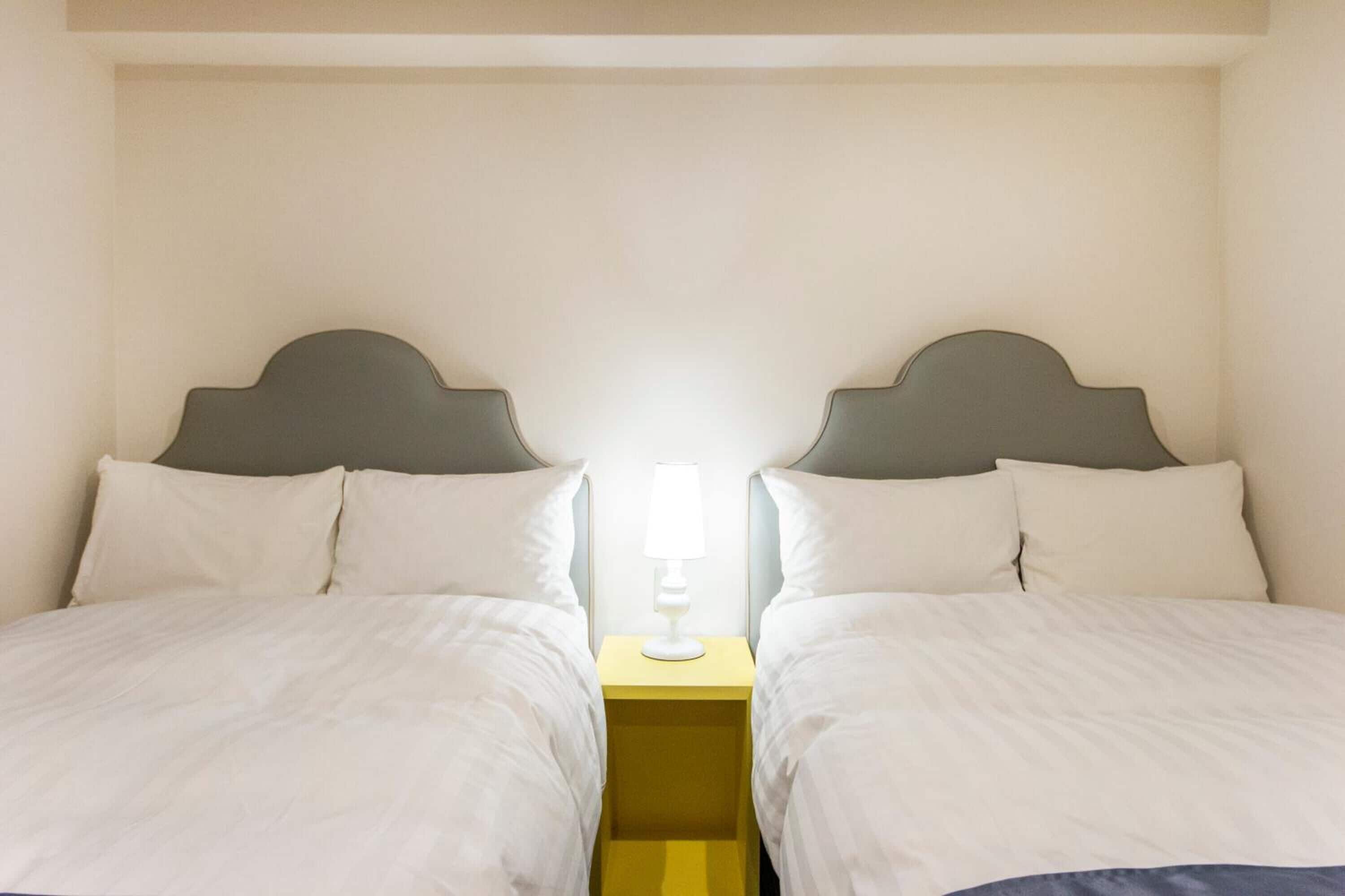 Un letto matrimoniale con testiera, un comodino con lampada e una parete semplice.