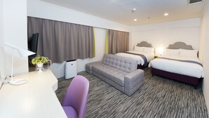 Una habitación de hotel con sofá, dos camas, escritorio y una silla.