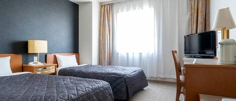 A hotel room with two beds, a desk with a television, and a chair.