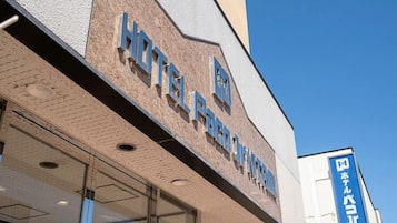 A hotel facade with a prominent sign, large windows, and a clear sky.