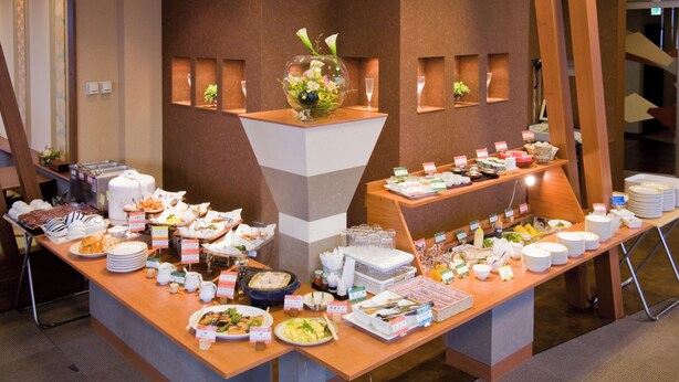 A buffet setup with various food items and a decorative centerpiece. - Hotel Paco Jr Kitami (Kitami)