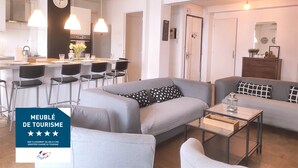 A modern living room with a grey sofa, a coffee table, and a dining area with a kitchen in the background. - 4(*) Standing flat, 3 bedrooms, private parking with AC near Panier Vieux-Port (Marseille)