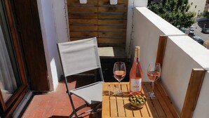 A small outdoor patio with a wooden table, two chairs, a bottle of wine, and a bowl of olives. - 4(*) Standing flat, 3 bedrooms, private parking with AC near Panier Vieux-Port (Marseille)