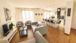 A living room with a sofa, chairs, a TV, and a coffee bar with a clock. - 4(*) Standing flat, 3 bedrooms, private parking with AC near Panier Vieux-Port (Marseille)