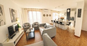 A living room with a sofa, chairs, a TV, and a coffee bar with a clock.