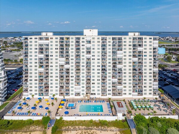 Ein Hochhaus-Hotel mit mehreren Balkonen, einem Swimmingpool und einem Parkplatz.