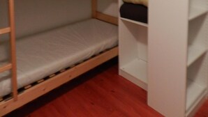 A bunk bed with a white mattress and a wooden frame. There is a white shelving unit with folded clothes. - 100m from ski slopes, parking, ski locker, 24m², Les 7 Laux (Le Pleynet)