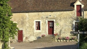 A stone building with a red door and window shutters, a sign reading "La Petite Moriniere," and a gravel path leading to the entrance.