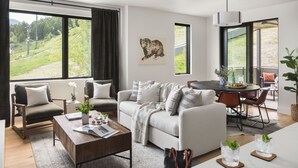 A modern living room with a sofa, armchairs, a coffee table, and a dining area with a table and chairs. - Outpost: One Town Hill 506 - Base of Snow King Mtn (Jackson)