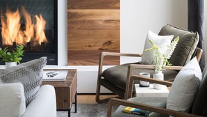 A modern living room with a fireplace, a wooden accent wall, a mounted cow skull, and comfortable seating. - Outpost: One Town Hill 506 - Base of Snow King Mtn (Jackson)