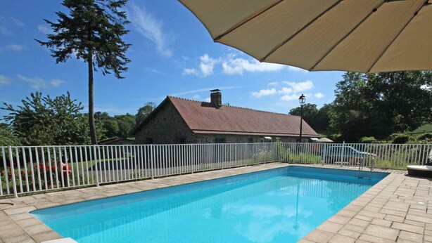 A rectangular swimming pool with a white fence surrounding it, a stone building in the background, and a clear blue sky. - Cottage with pool and wifi in Ste Honorine (Sainte-Honorine-la-Guillaume)