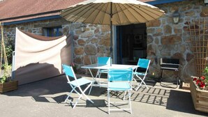 An outdoor patio with a table and chairs, a large umbrella, and a stone wall. - Cottage with pool and wifi in Ste Honorine (Sainte-Honorine-la-Guillaume)