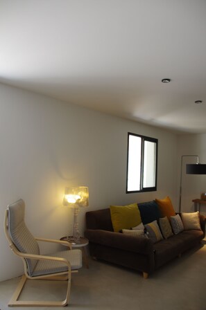 Relax in a serene space with a contemporary sofa, armchair, and side table, surrounded by a large window.