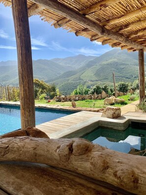 A pool area with a wooden deck, stone pathway, and a view of mountains in the background. - Casa I&B (Peri)