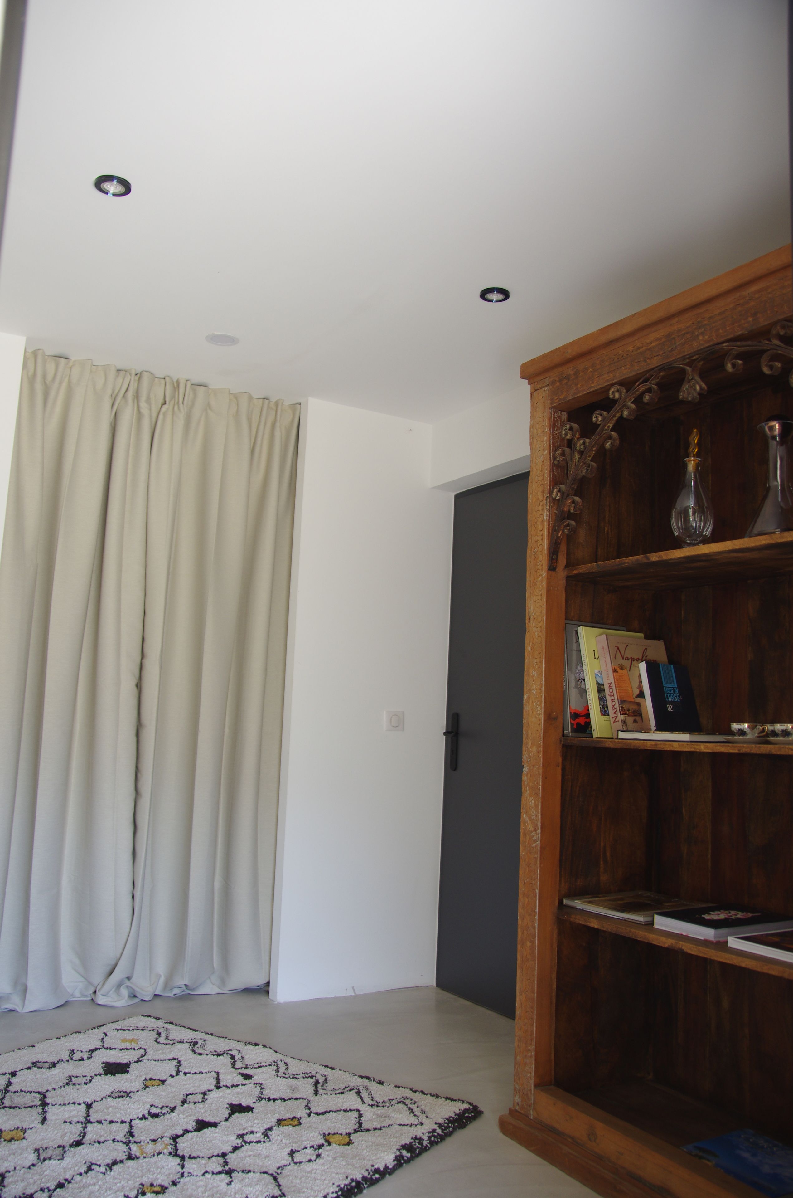 A room with a wooden bookshelf, a patterned rug, and a door with a curtain.