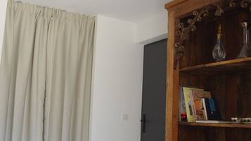 A room with a wooden bookshelf, a patterned rug, and a door with a curtain.