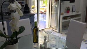 Eine moderne Küche mit weißen Schränken, einem Esstisch mit Stühlen, einer Topfpflanze mit Orchideen und einem Weinglas.
