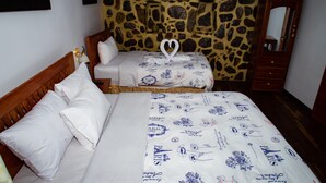Una camera da letto con parete in pietra, un letto con copripiumino a tema Parigi, una testiera in legno e un comodino con lampada.