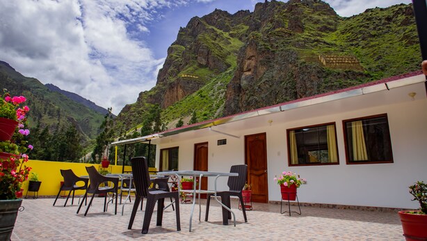 Una terrazza con posti a sedere all'aperto, uno sfondo montuoso e un edificio con tetto rosso.