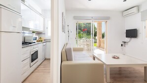 Une cuisine moderne avec des meubles blancs et un coin repas comprenant une table et un banc, tous deux blancs.