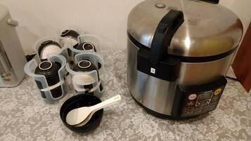 Une cuisine équipée d’un cuiseur à riz en acier inoxydable, d’un distributeur d’eau et d’une machine à café.
