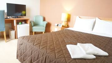 A hotel room with a bed, a desk, a chair, a television, and a nightstand with a lamp.