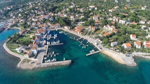 An aerial view of a coastal town with a marina, residential buildings, and clear blue waters. - Apartments Del Sole (Mali Losinj)