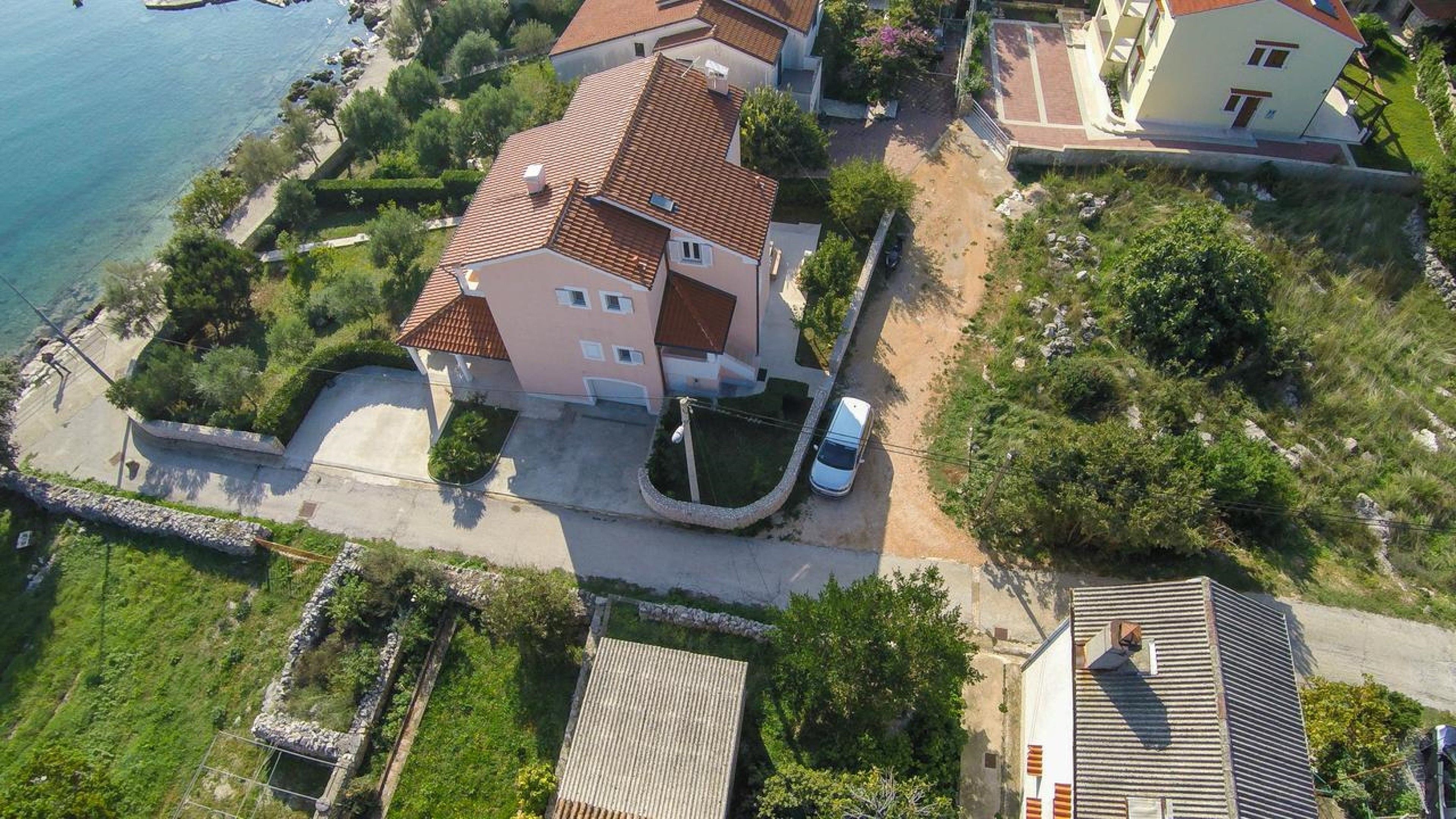 Vue aérienne d’un quartier résidentiel, avec une maison dotée d’un toit en tuiles, d’une allée et d’une voiture garée.