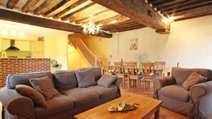 Ein gemütliches Wohnzimmer mit Holzboden, zwei Sofas, einem Couchtisch und einem Essbereich mit Stühlen und Tisch.