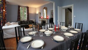 A dining room with a table set for six, a sofa, and a fireplace.