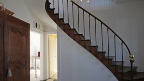 A staircase with a wooden handrail and black balusters, leading to an upper floor.