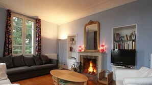 A living room with a fireplace, a sofa, a coffee table, and a bookshelf.